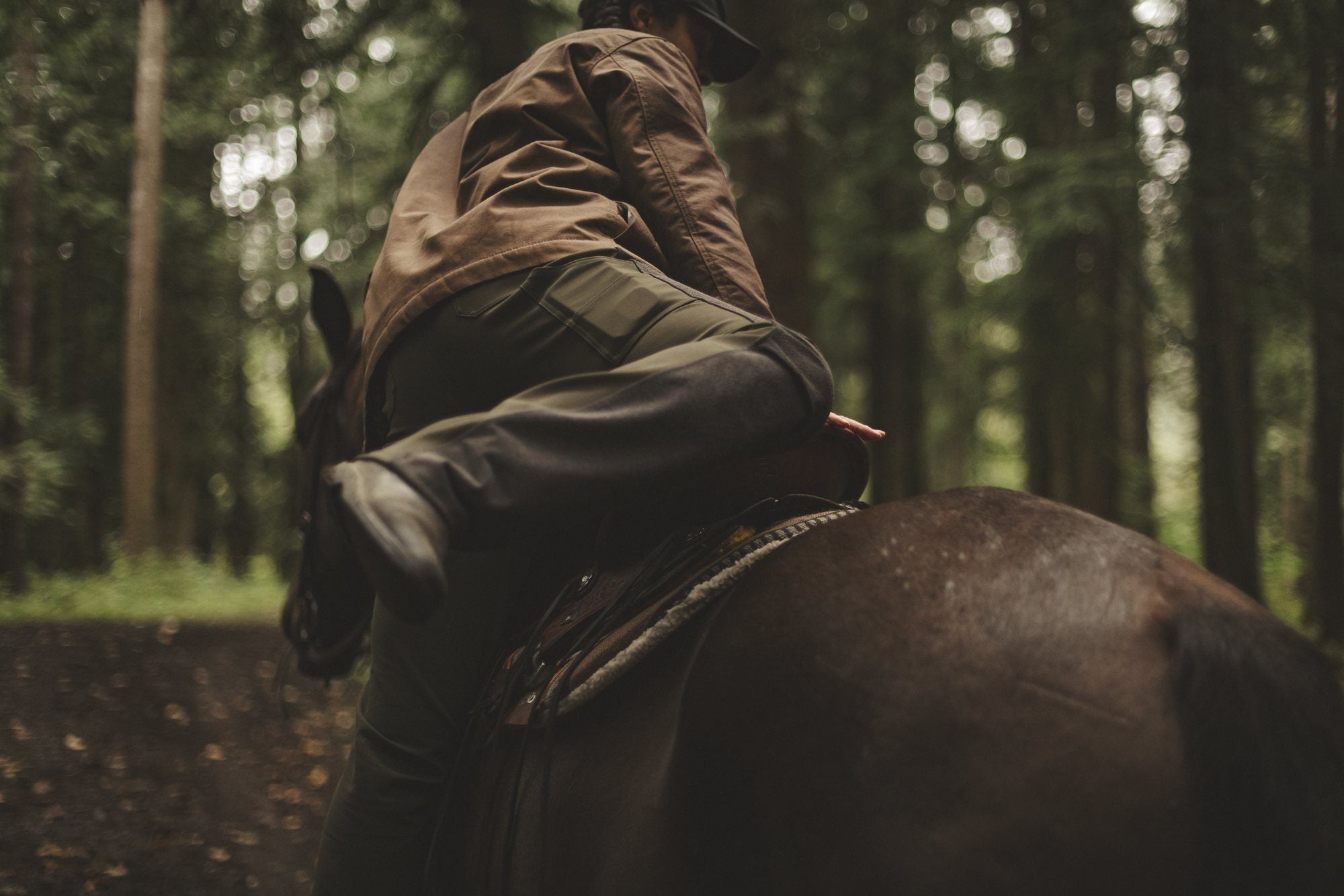 A rider in The Bushwacker swings up onto a dark horse in the forest